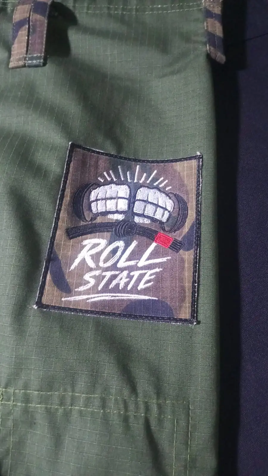 Detalle del parche bordado de Roll State cosido sobre el pantalón verde militar del GI